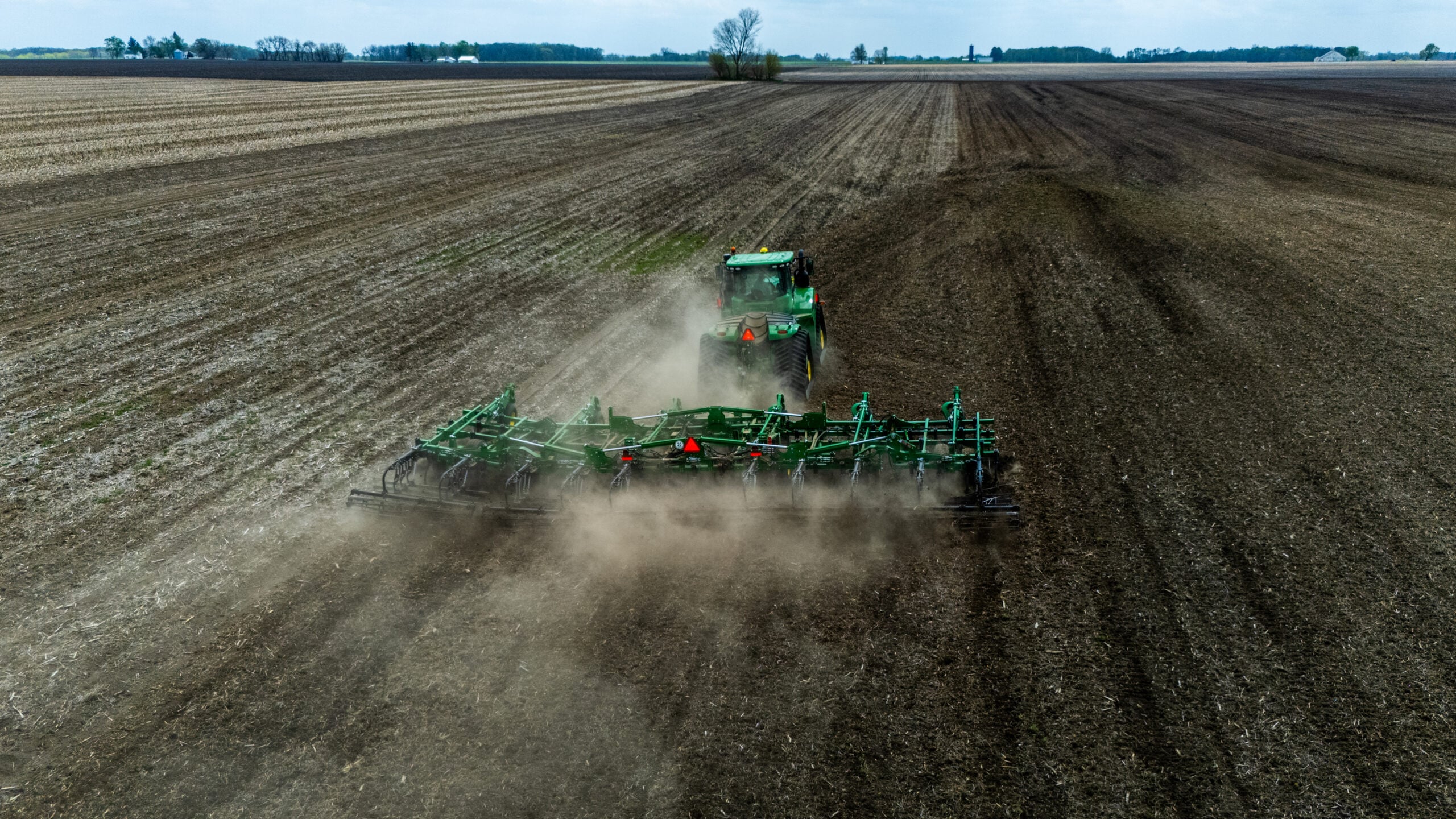 Drone photo of tractor pulling field cultivator through soil near Jacksonville Illinois during spring plowing season