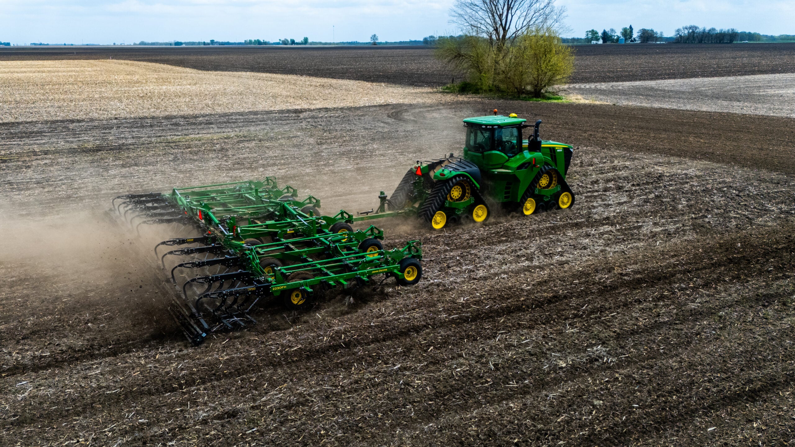 Aerial drone photo of tractor and field cultivator working rich Illinois soil with lone tree and farmland in background near Jacksonville IL