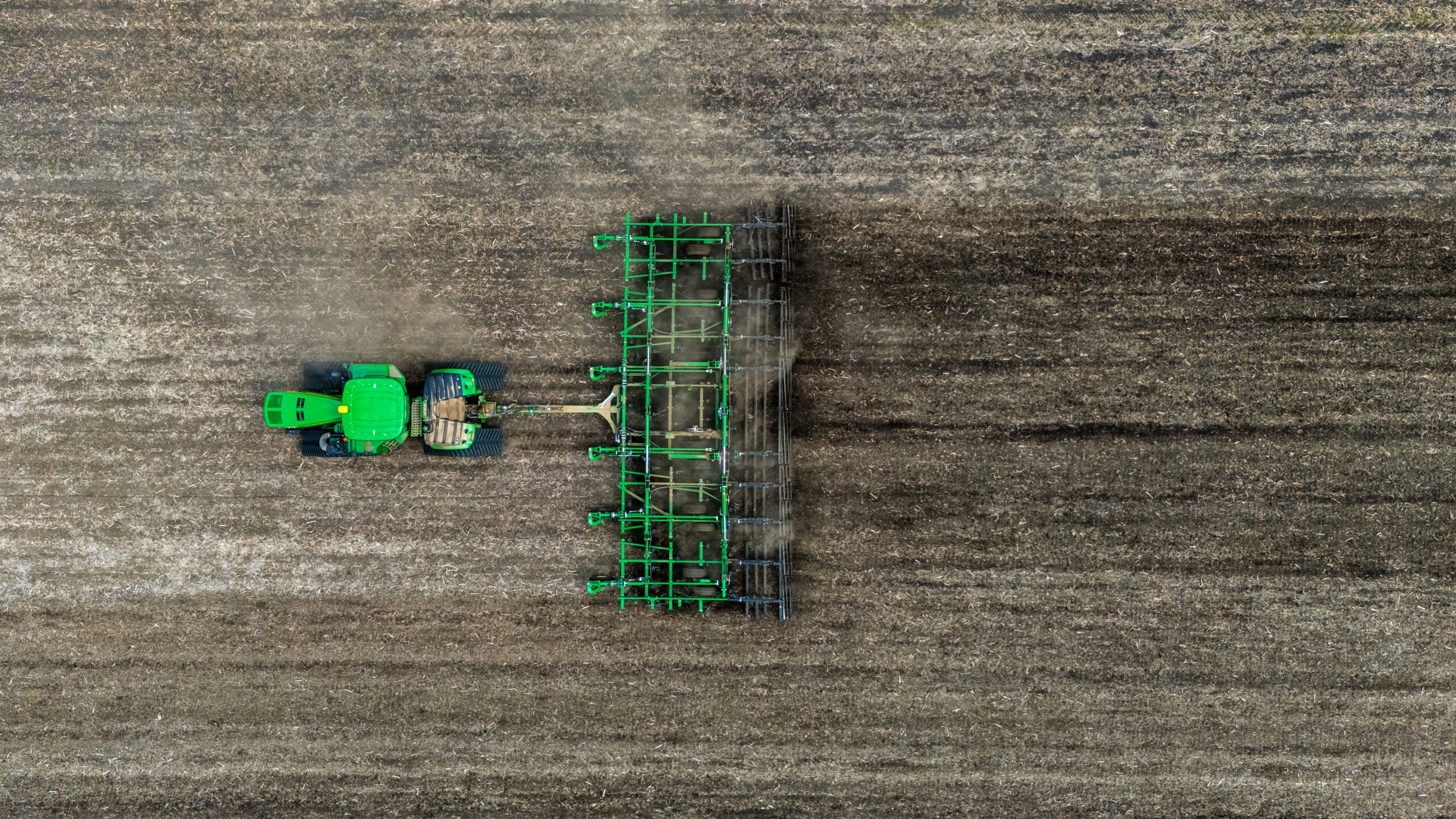 Birds eye overhead drone photo of tractor and cultivator showing dramatic contrast between worked and unworked soil in Central Illinois field