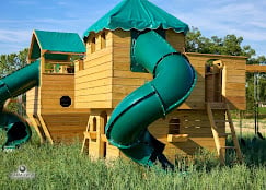 Wooden climbing castle and ship playground with green slides at Buena Vista Farms campground in Chapin Illinois