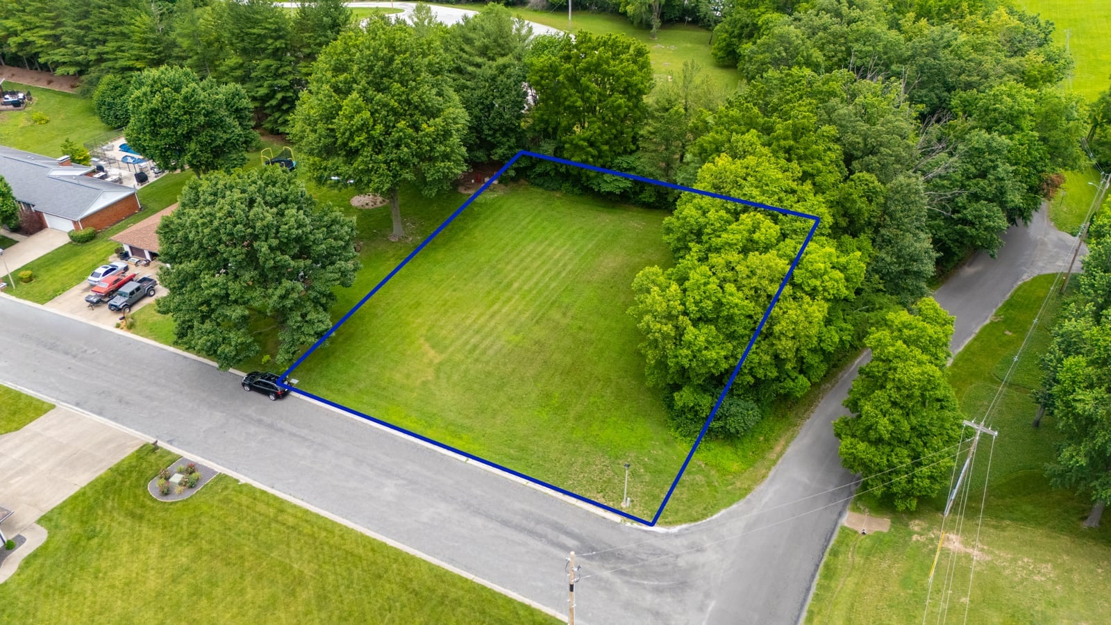 Aerial drone photo of a vacant residential lot for sale with a blue property line boundary overlay in Jacksonville, Illinois