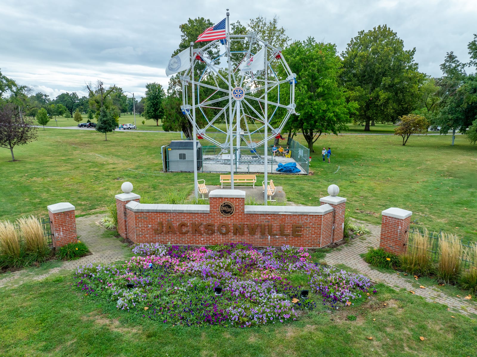 Aerial drone photo of the Big Eli Ferris Wheel behind the brick Jacksonville Illinois welcome sign and flower beds in Community Park