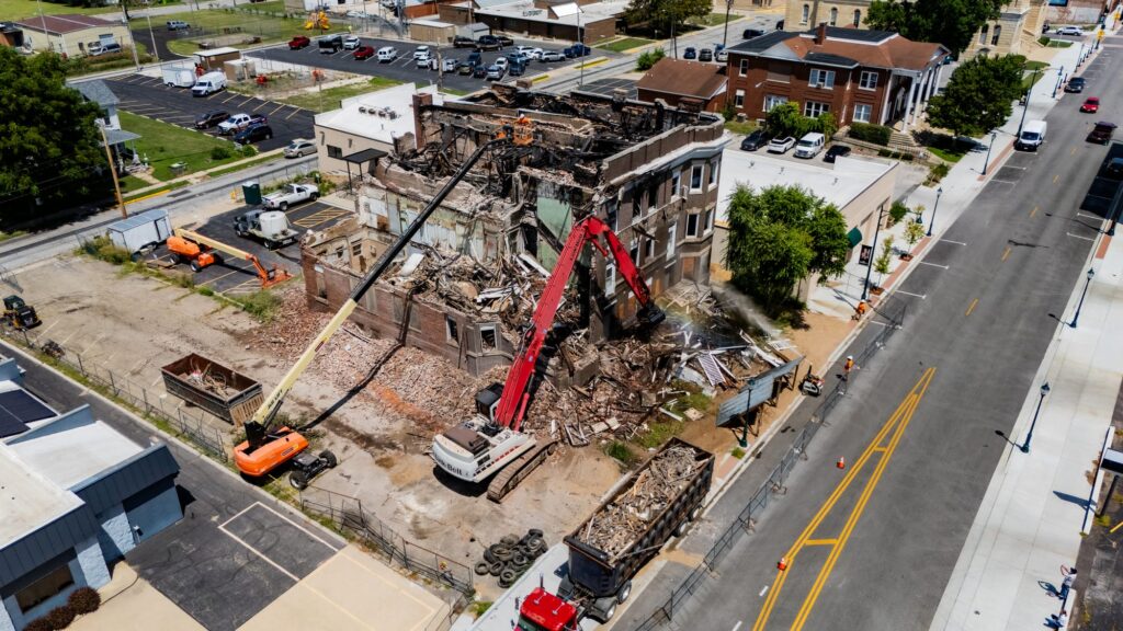Aerial drone photo of the Cherry Apartments demolition at 342 W State Street Jacksonville IL, high-reach excavator tearing into the fire-damaged brick building