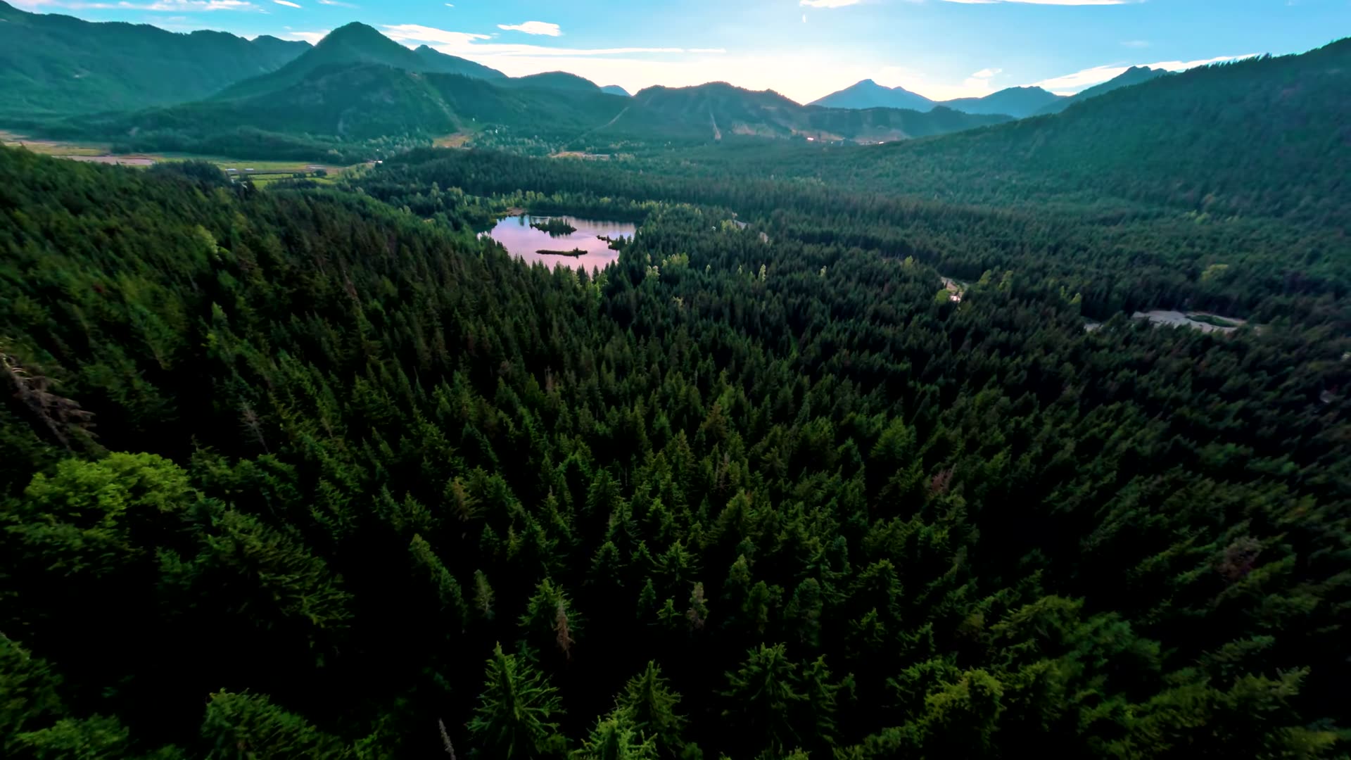 Gold Creek Pond from the air, framed by evergreen forest and Cascade peaks