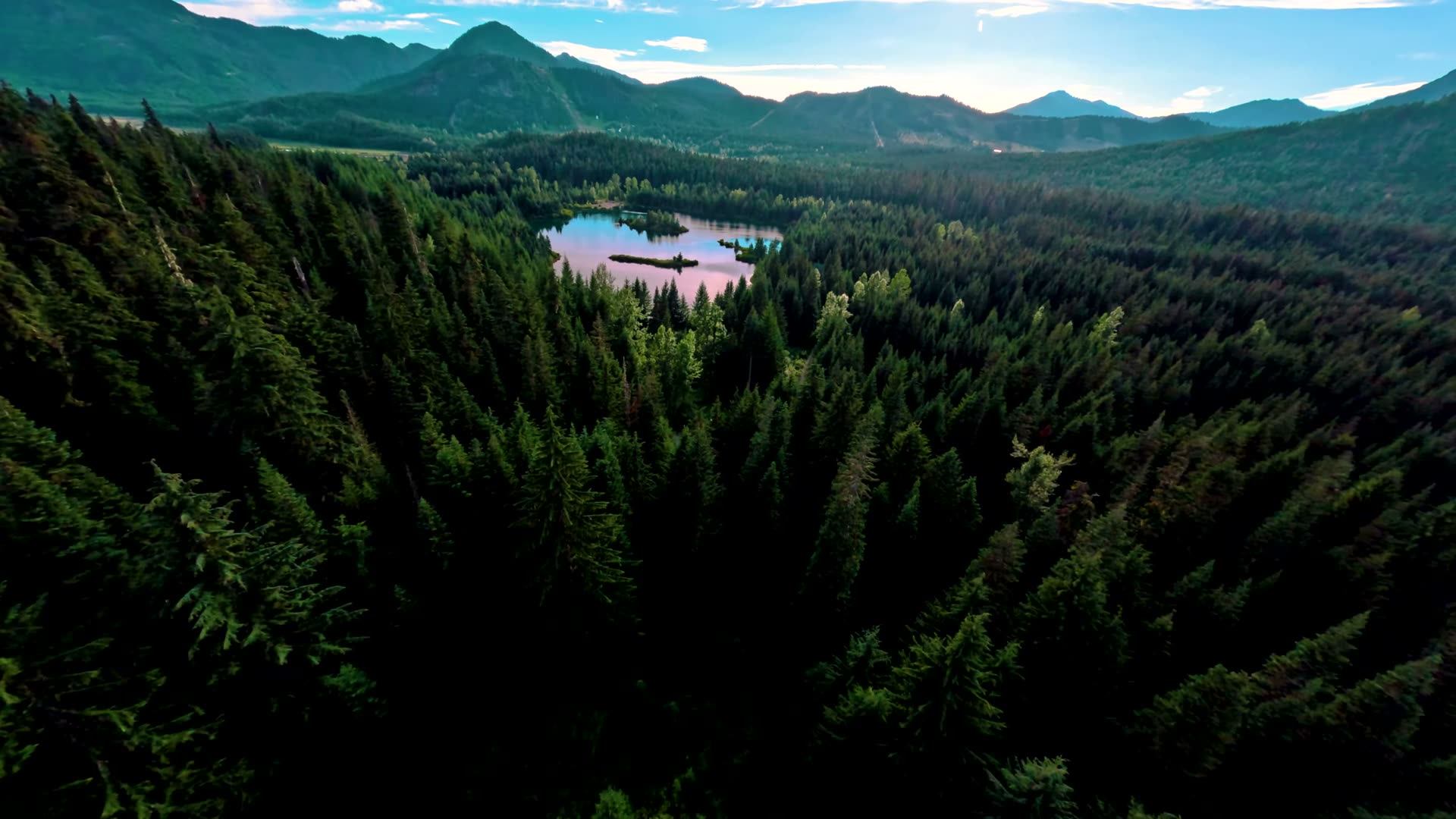 Drone photo of Gold Creek Pond with a wide Cascade Mountain panorama behind it