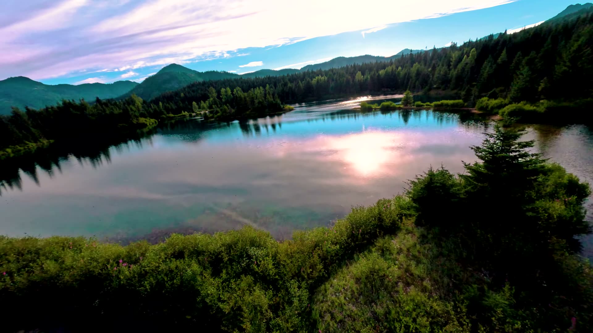 Low aerial pass over Gold Creek Pond with sun glare on the water