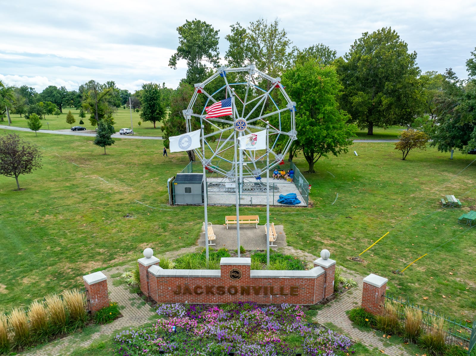 Brick Jacksonville sign with the Big Eli Ferris Wheel and flags rising behind it in Community Park