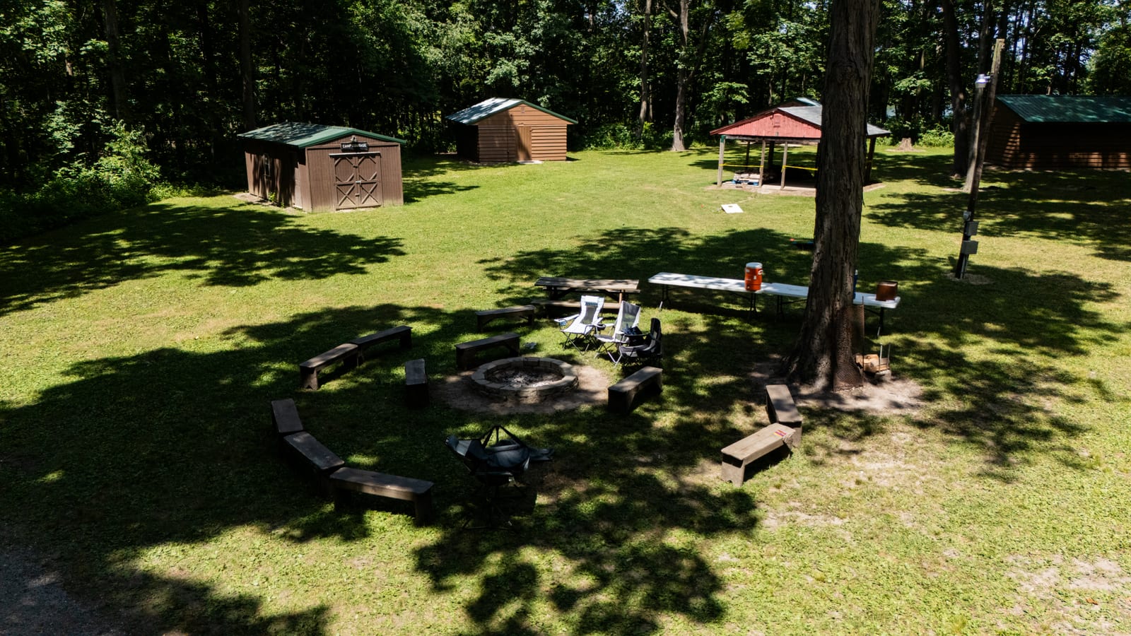 Council campfire ring with wooden bench seating under shade trees at Western Illinois Youth Camp in Jacksonville Illinois