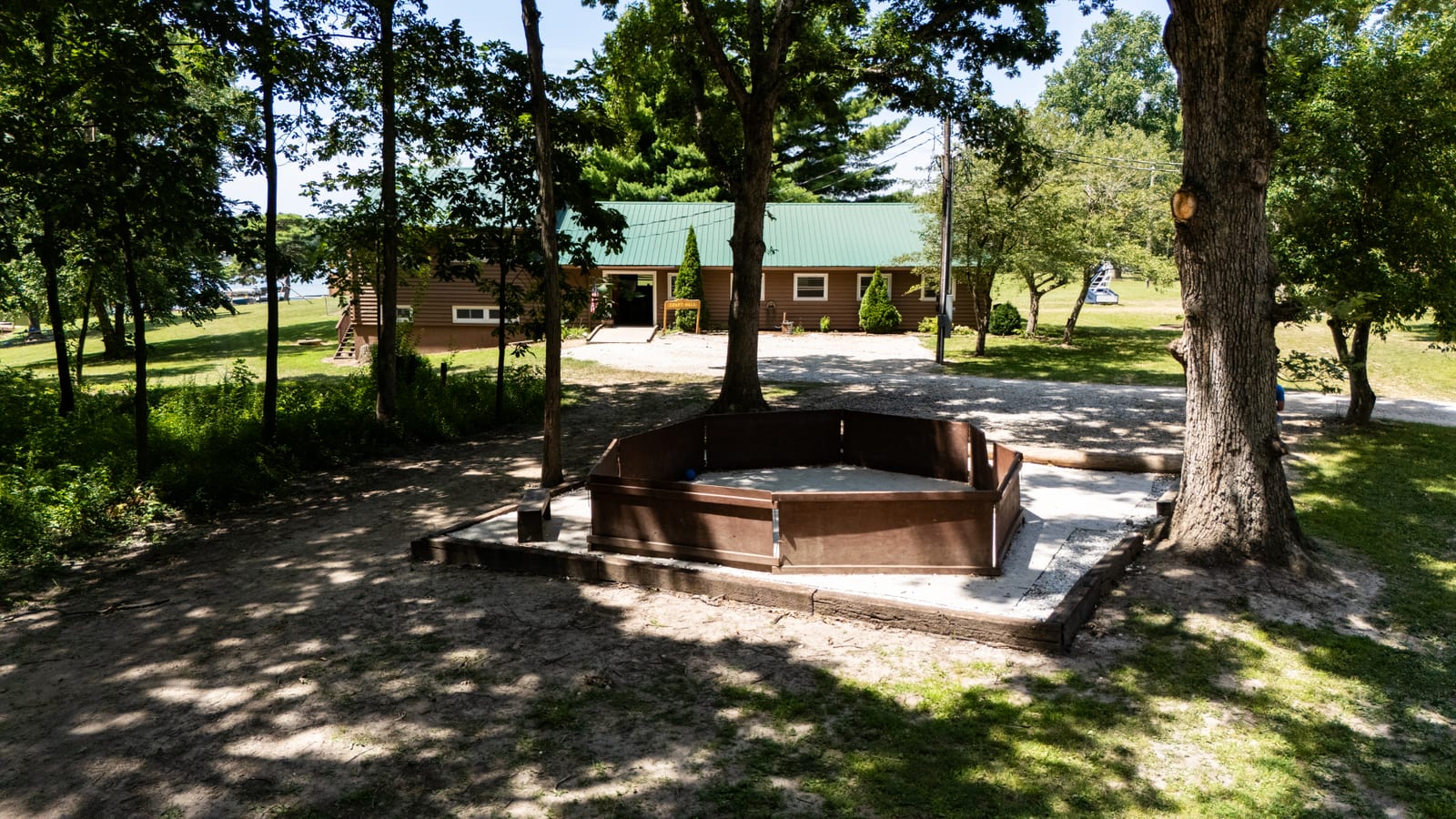 Octagonal gaga ball pit beneath mature oak trees at Western Illinois Youth Camp, aerial drone photo