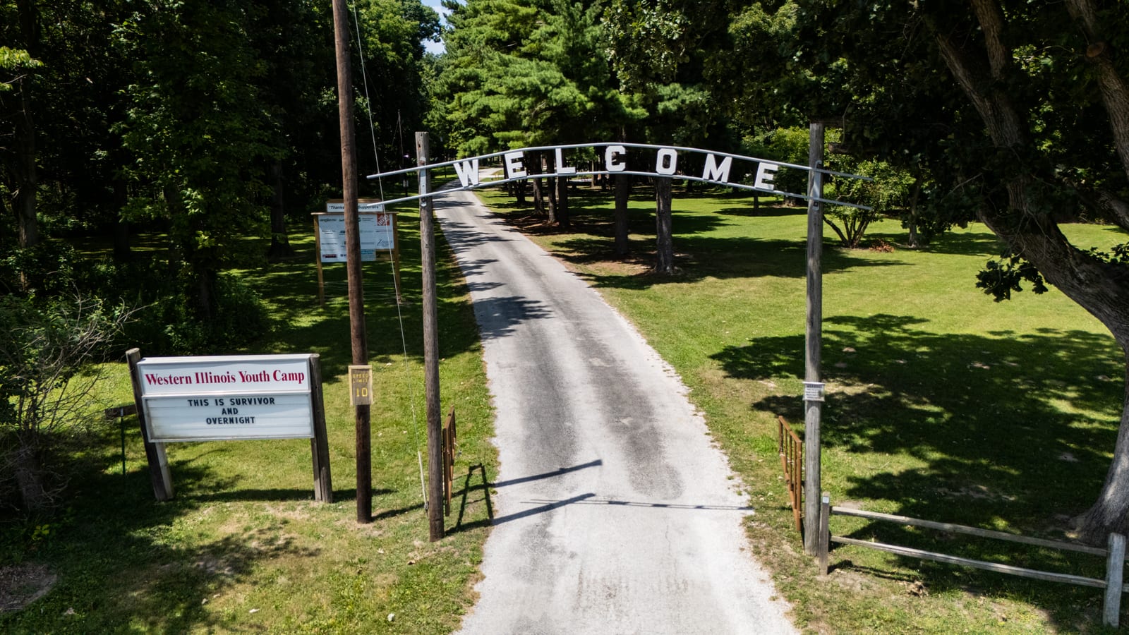 WELCOME arch over the tree-lined entrance lane at Western Illinois Youth Camp in Jacksonville IL, seen by drone