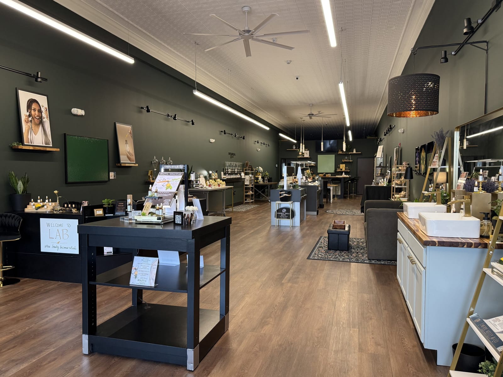 Interior of Cheryl Kelly & Co. clean beauty shop in Jacksonville IL, painted in Magnolia's 1905 Green, with wood floors and product display tables
