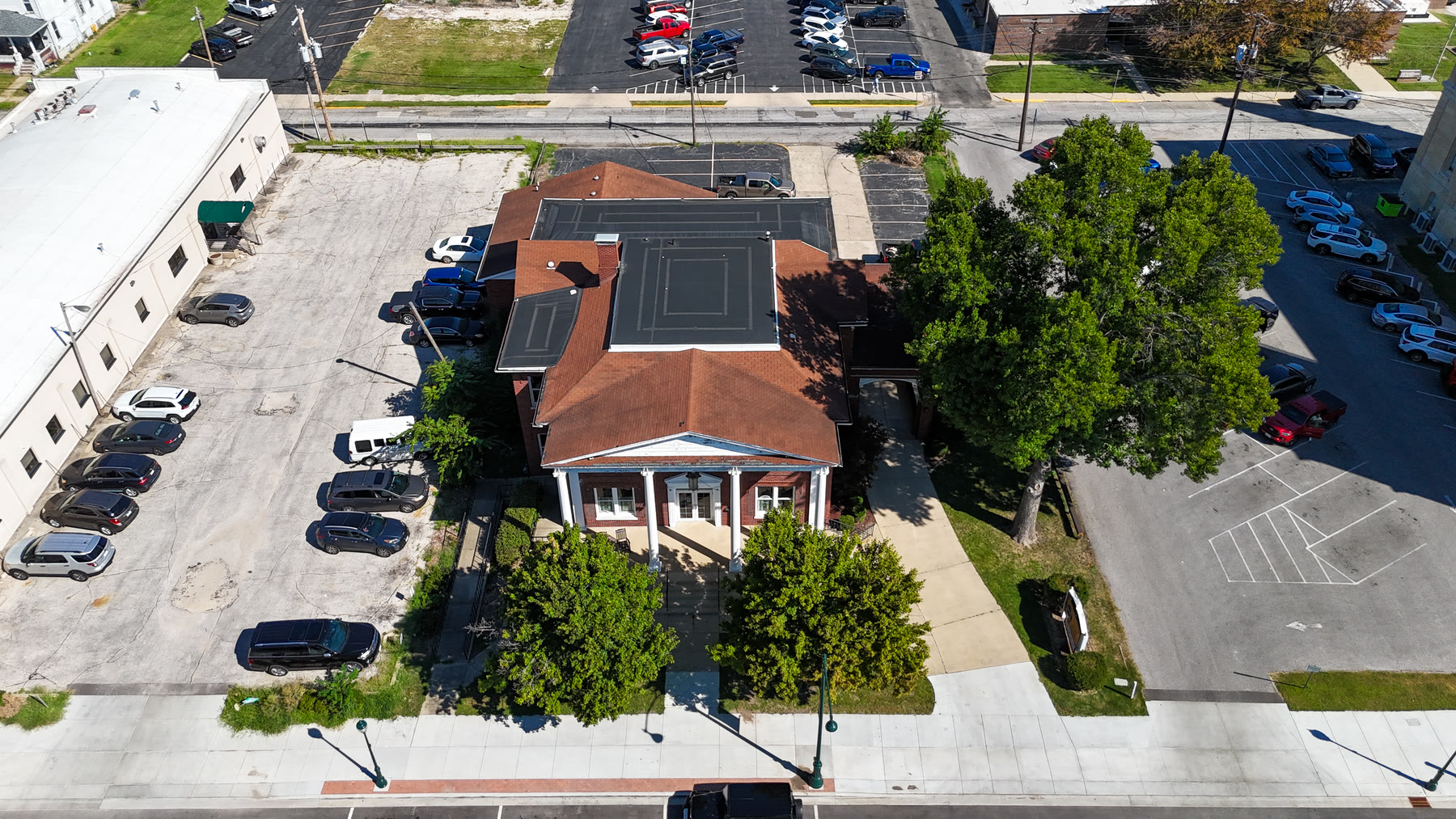 Top-down drone photo of the Gillham House roof, the columned front porch, mature trees, and the parking lot beside the building in Jacksonville, Illinois