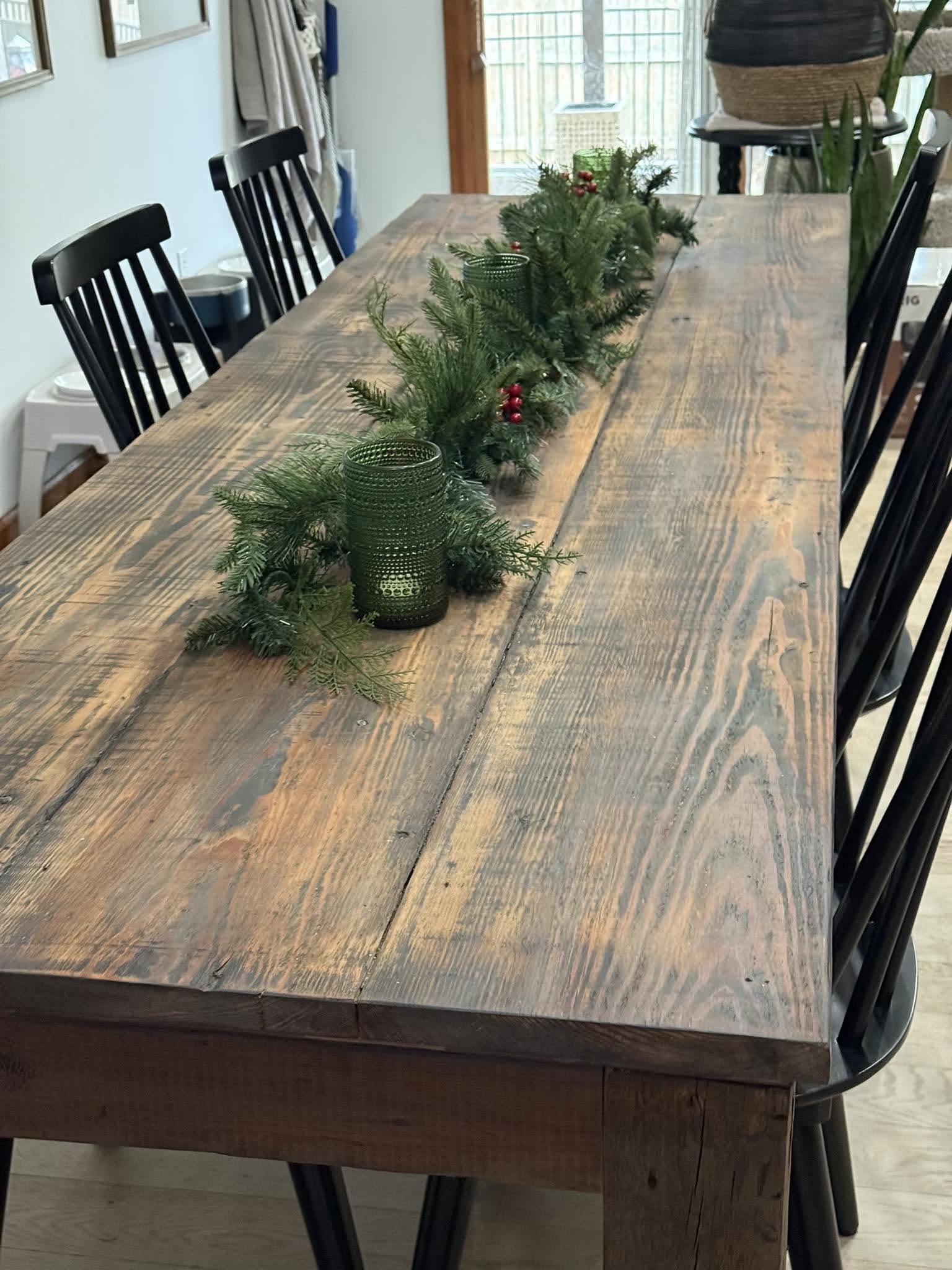 Reclaimed wood dining table with black chairs and a greenery runner down the center, built by Jacksonville Transfer Company in Jacksonville, Illinois